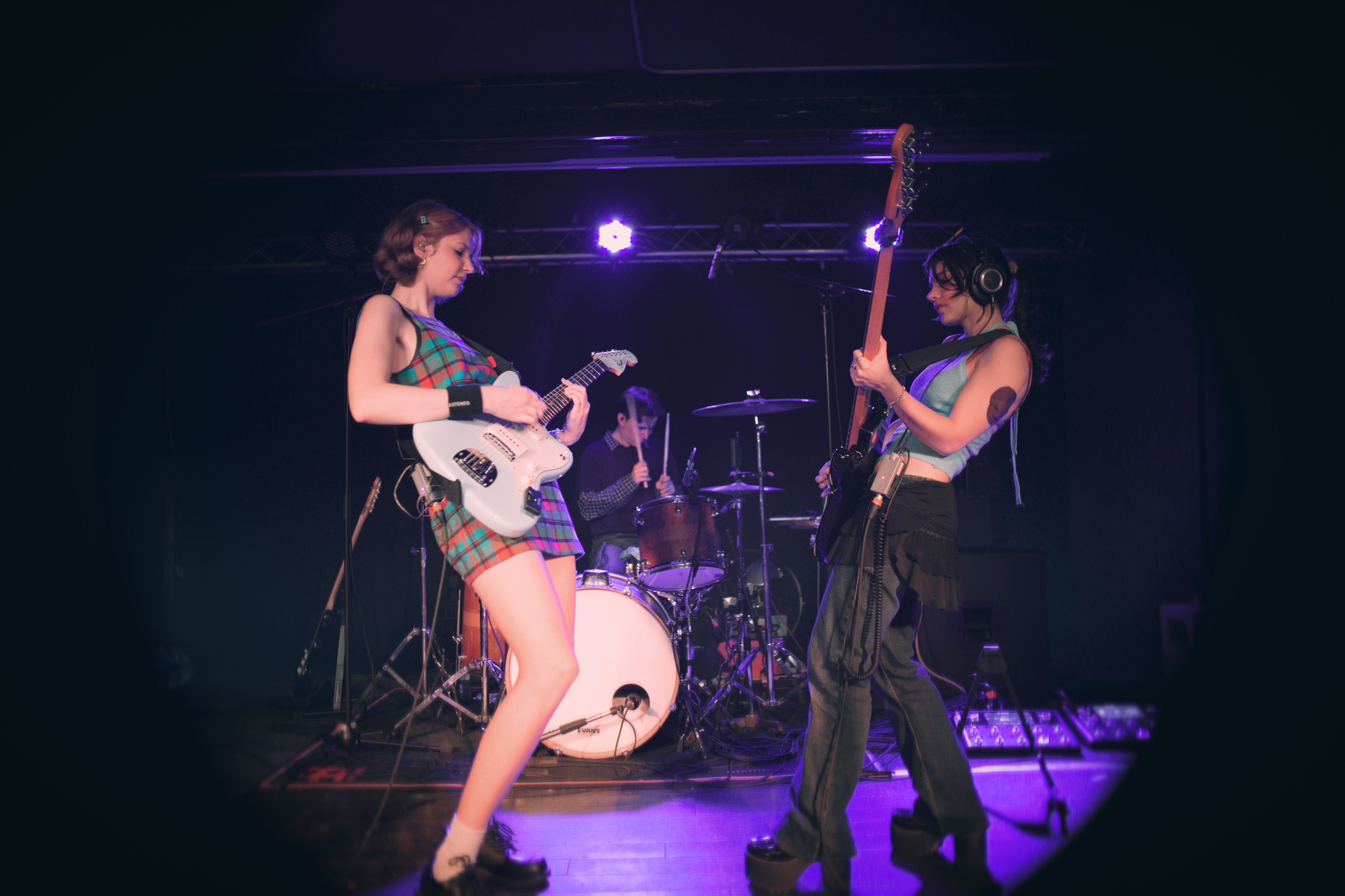 Pacifica facing each other onstage, with an upright bass neck and a drummer between them under violet light